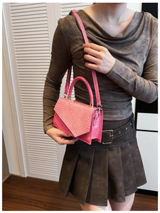 Detail of pink small square bag with snake pattern texture and crossbody strap on model