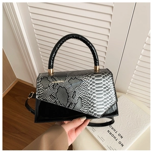 Detail of snake pattern and black patent leather mix on geometric crossbody bag