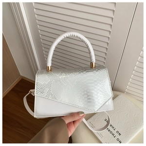 Detail of white square handbag with snake pattern texture and gold hardware accents