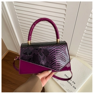 Detail of purple faux snakeskin flap and glossy patent leather on chic crossbody bag