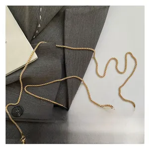 Close-up of sleek golden chain strap and round metal handle on a stylish handbag