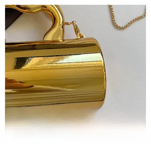 Macro view of metallic gold cylindrical handbag with streamlined handle and chain strap