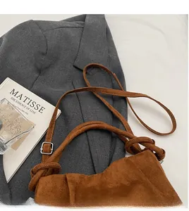 Détail de la bandoulière réglable avec boucle argentée sur un sac nuage en daim marron