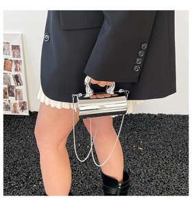 Sleek mirror silver cylindrical handbag with a liquid metal handle and chain strap