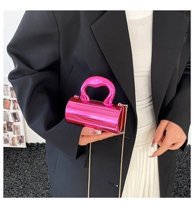 Bright pink mirror cylindrical mini handbag with gold chain strap on black blazer model
