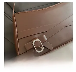 Dettaglio borsa a spalla in pelle marrone con fibbia ovale argento e cinturini decorativi