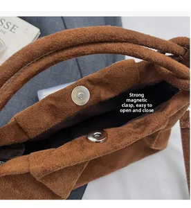 Détail macro du sac en daim marron montrant un fermoir magnétique puissant et sa structure