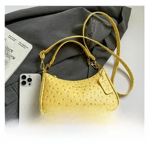 Dettaglio della borsa gialla texture struzzo con tracolla rimovibile e logo dorato