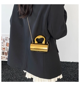 Chic gold cylindrical mini bag featuring heart-shaped metal handle and slim chain strap