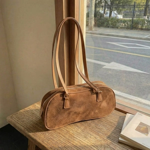 Vintage dark brown suede shoulder bag on a wooden bench with natural lighting
