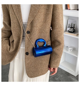 Close-up of electric blue metallic cylinder bag with elegant gold chain strap