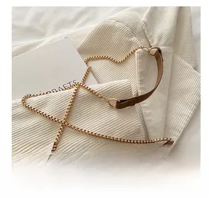 Detail of brown leather strap with golden metal chain on a woven texture shoulder bag