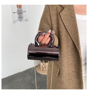 Close-up of a purple cylindrical acrylic handbag with golden chain and mirror finish
