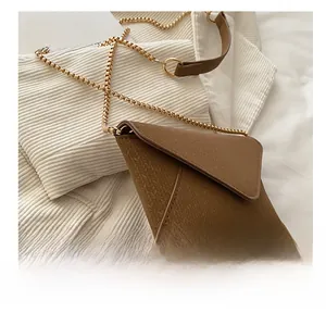 Detail of brown envelope crossbody bag with herringbone texture and gold chain strap