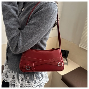 Dettaglio della borsa a spalla in pelle rossa con fiocco decorativo e fibbia in metallo
