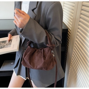 Détail d'un sac plissé en daim marron avec poignée nouée et bandoulière amovible