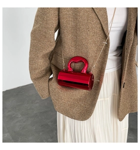 Close-up of bright red cylindrical handbag with metallic finish and gold chain strap