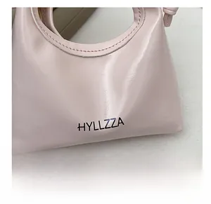 Dettaglio della mini borsa rosa lucida con logo HYLLZZA e design con manico superiore