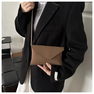 Detail showing brown chevron embossed envelope bag with elegant gold chain shoulder strap