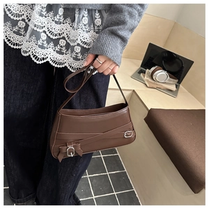Dettaglio borsa baguette in pelle testa di moro con cinturini e fibbie argentate