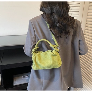 Détail du sac à main plissé vert vif avec poignée à nœud sur modèle en tailleur gris