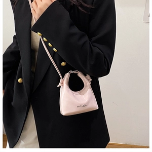 Dettaglio della borsa a mezzaluna in pelle rosa lavanda su un blazer nero classico