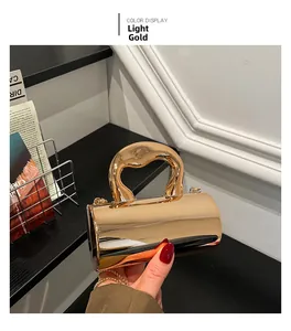 Close-up of a light gold cylindrical clutch bag with a thick circular metal handle