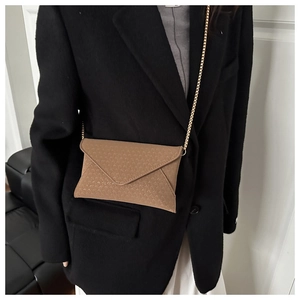 Brown envelope crossbody bag with letter A pattern and gold chain on black blazer