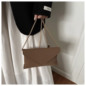 Detailed view of a brown envelope clutch with fine geometric texture and gold chain strap