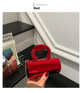 Detail of red cylindrical mini handbag with chunky top handle and gold chain strap