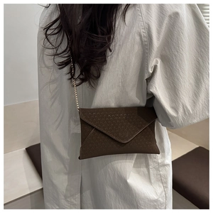 Model view of a dark brown envelope crossbody bag with a gold chain strap and textured finish