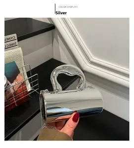 Detail of silver cylindrical handbag with metallic mirror finish and wide curved handle