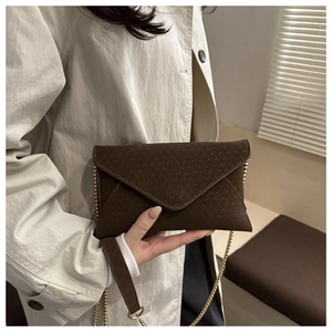 Detail of dark brown envelope crossbody bag with geometric texture and gold chain strap