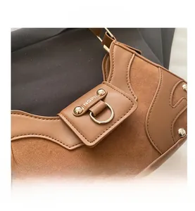 Close-up of caramel leather shoulder bag with metallic rivets and gold D-ring detail