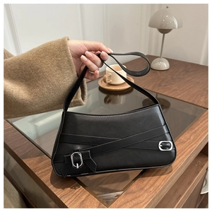 Dettaglio della borsa baguette in pelle nera con cinghie decorative e fibbie in metallo