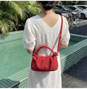 Détail du sac à main rouge plissé avec poignée nouée et bandoulière sur mannequin