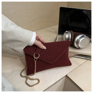 Detail of burgundy textured leather envelope bag with gold ring buckle and chain strap