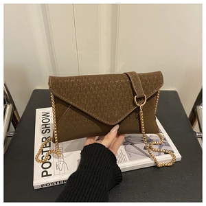 Detailed view of brown textured envelope bag with golden ring clasp and chain strap