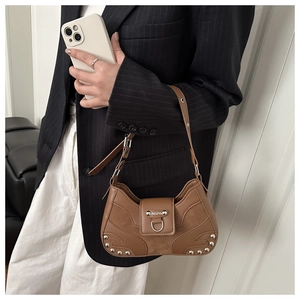 Detail of brown leather motorcycle bag featuring silver rivets and metal buckle accent