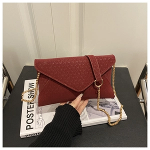 Detail of dark red envelope bag with V-shaped texture and gold chain strap