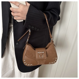 Brown retro shoulder bag with silver studs worn by a model in a black striped blazer