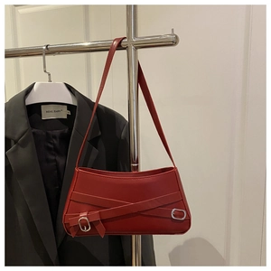 Dettaglio borsa rossa con cintura decorativa, fibbia in metallo e fiocco laterale