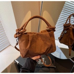Détail d'un sac à main en daim marron plissé avec poignée nouée et bandoulière élégante