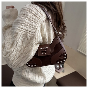 Detail of vintage brown motor bag with silver rivets and metal buckle on white sweater