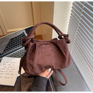 Détail d'un sac à main plissé marron foncé avec poignée nouée et bandoulière réglable