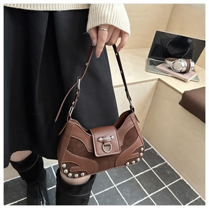 Detail of vintage brown leather bag with silver studs and metal ring on wooden stairs