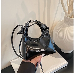 Dettaglio mini borsa nera lucida a pieghe con logo HYLLZZA e sottile tracolla di classe