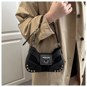 Detail of black rivet shoulder bag featuring mixed leather textures and silver hardware