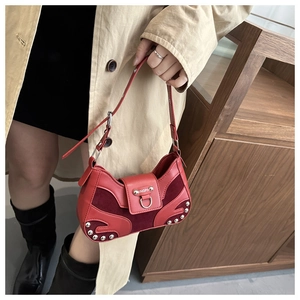 Detail of red vintage shoulder bag with silver studs and metal ring on a model