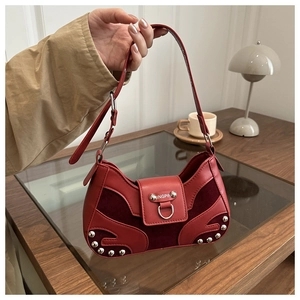 Detail of burgundy textured leather shoulder bag with silver rivet accents and ring buckle